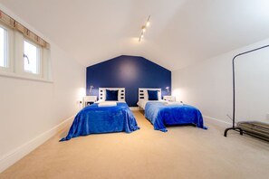 Ein Schlafzimmer mit zwei Betten, einer geneigten Decke und einem Fenster mit Jalousien.
