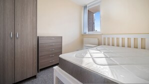 A bedroom with a bed, a wardrobe, a dresser, and a window with a view. - 4-bed Maisonette With Balcony (London)