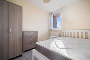 Ein Schlafzimmer mit Bett, Kleiderschrank, Kommode und einem Fenster mit Aussicht.