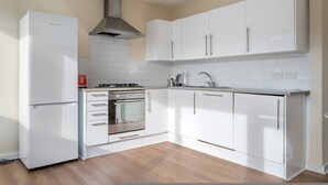 A modern kitchen with white cabinets, a built-in oven, a stainless steel range, and a refrigerator. - 4-bed Maisonette With Balcony (London)