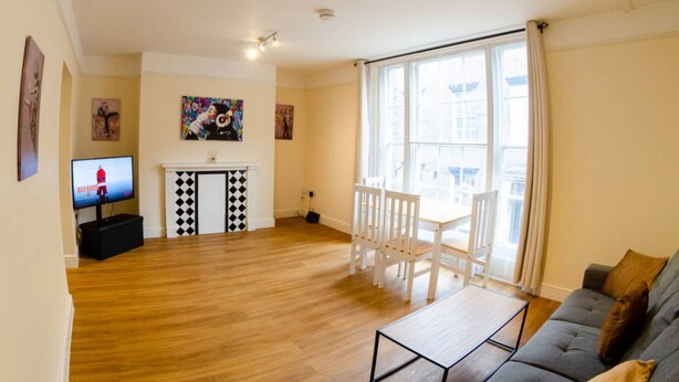 Una sala de estar con sofá, televisor, chimenea y ventana grande.