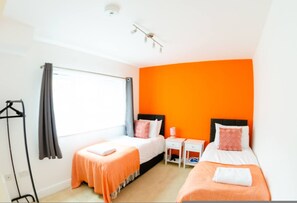 A hotel room with two beds, a window, a wardrobe, and a small table. - Central Ipswich Stay for 4 Budget-friendly Convenient (Ipswich)