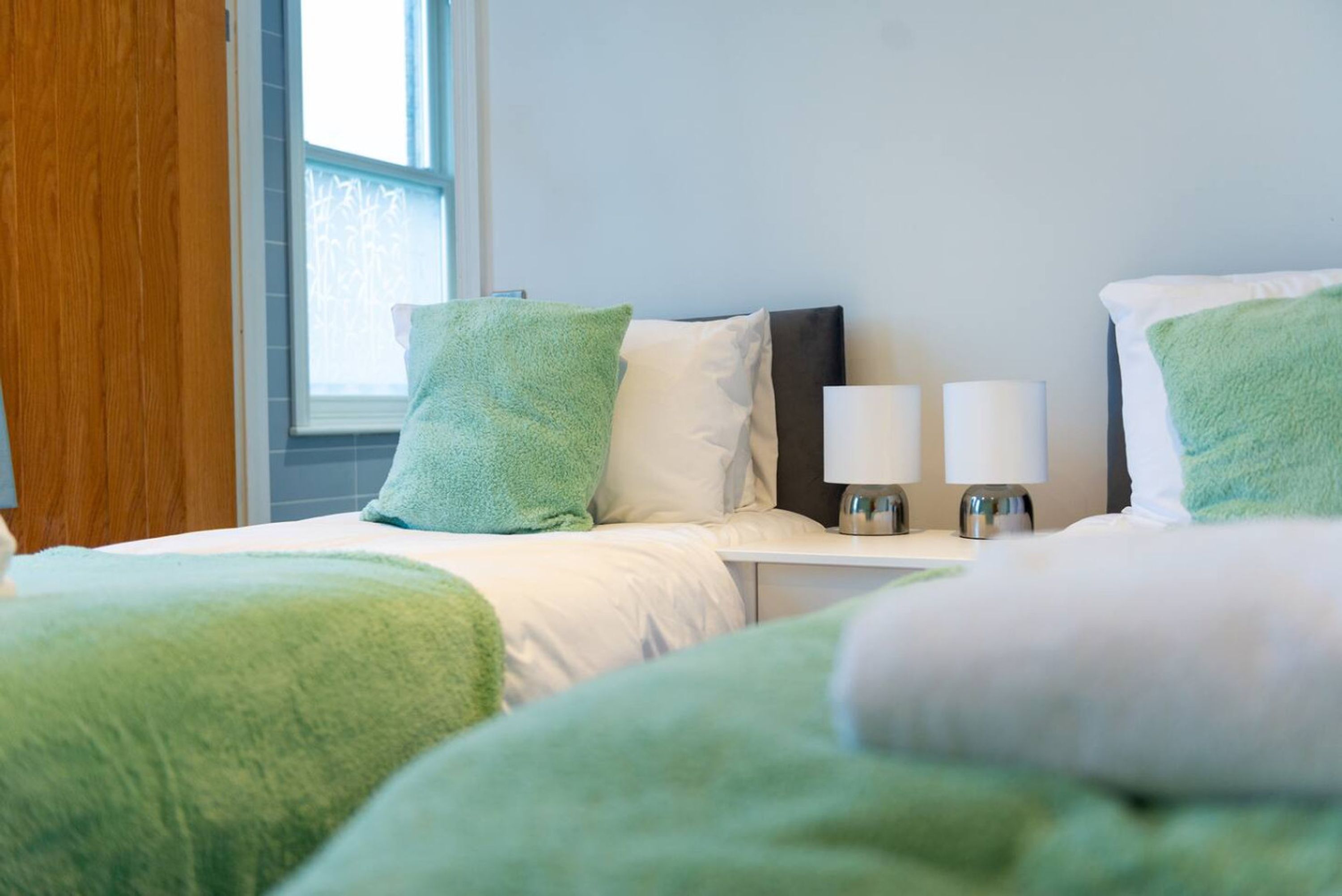 Une chambre d’hôtel avec un lit, deux lampes de chevet, une fenêtre et un rideau.
