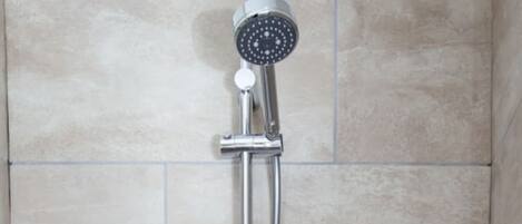 Una ducha con tres cabezales de ducha manuales.