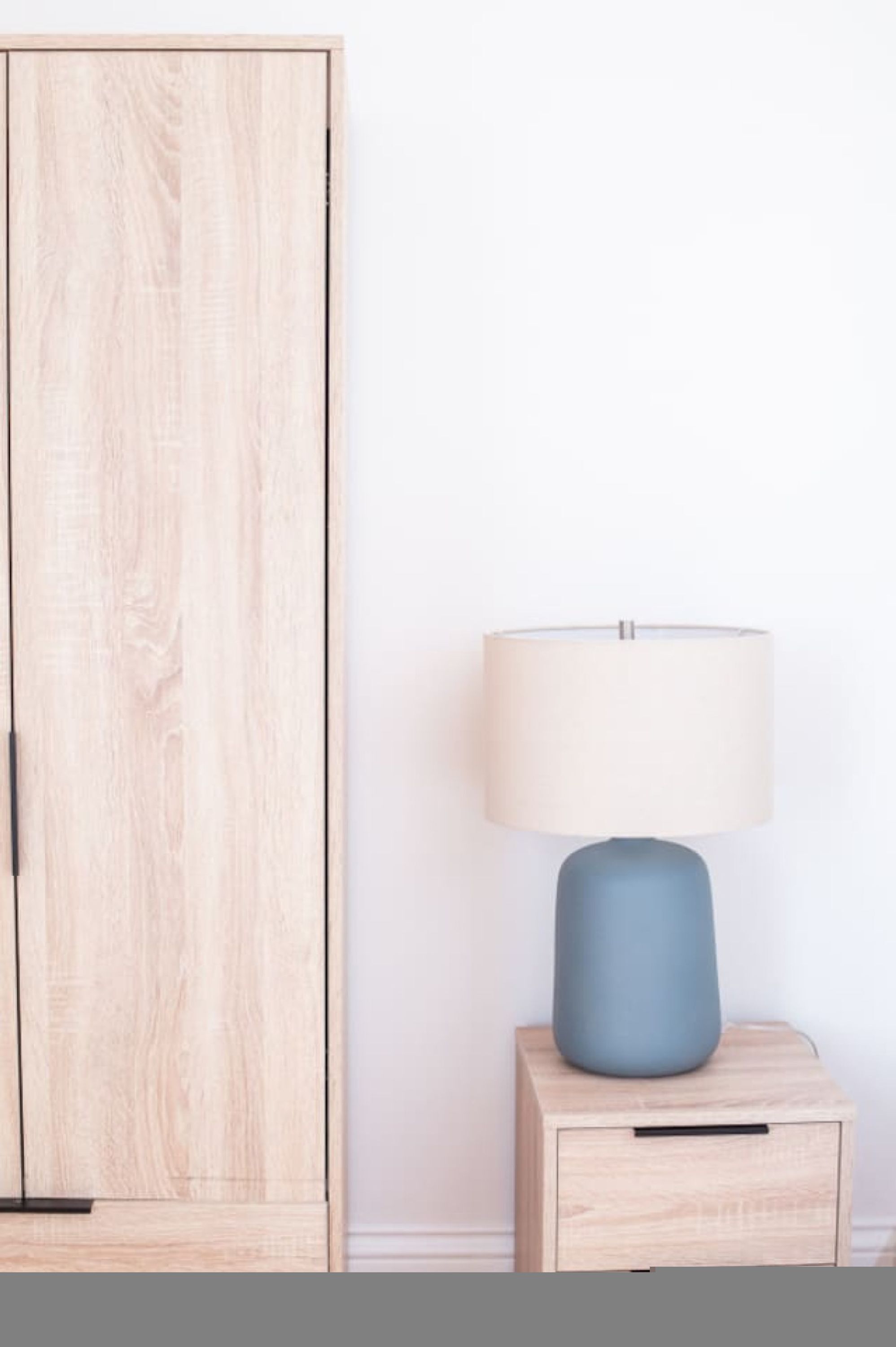 Ein Holzschrank mit Schublade und ein Nachttisch mit Lampe.