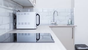 Eine moderne Küche mit integriertem Mikrowellenherd, Spüle und Mülleimer.