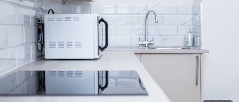 A modern kitchen with a built-in microwave, a sink, and a trash bin.