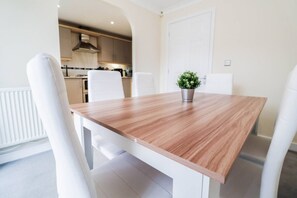 Ein Essbereich mit einem Holztisch, weißen Stühlen und einer Zimmerpflanze.