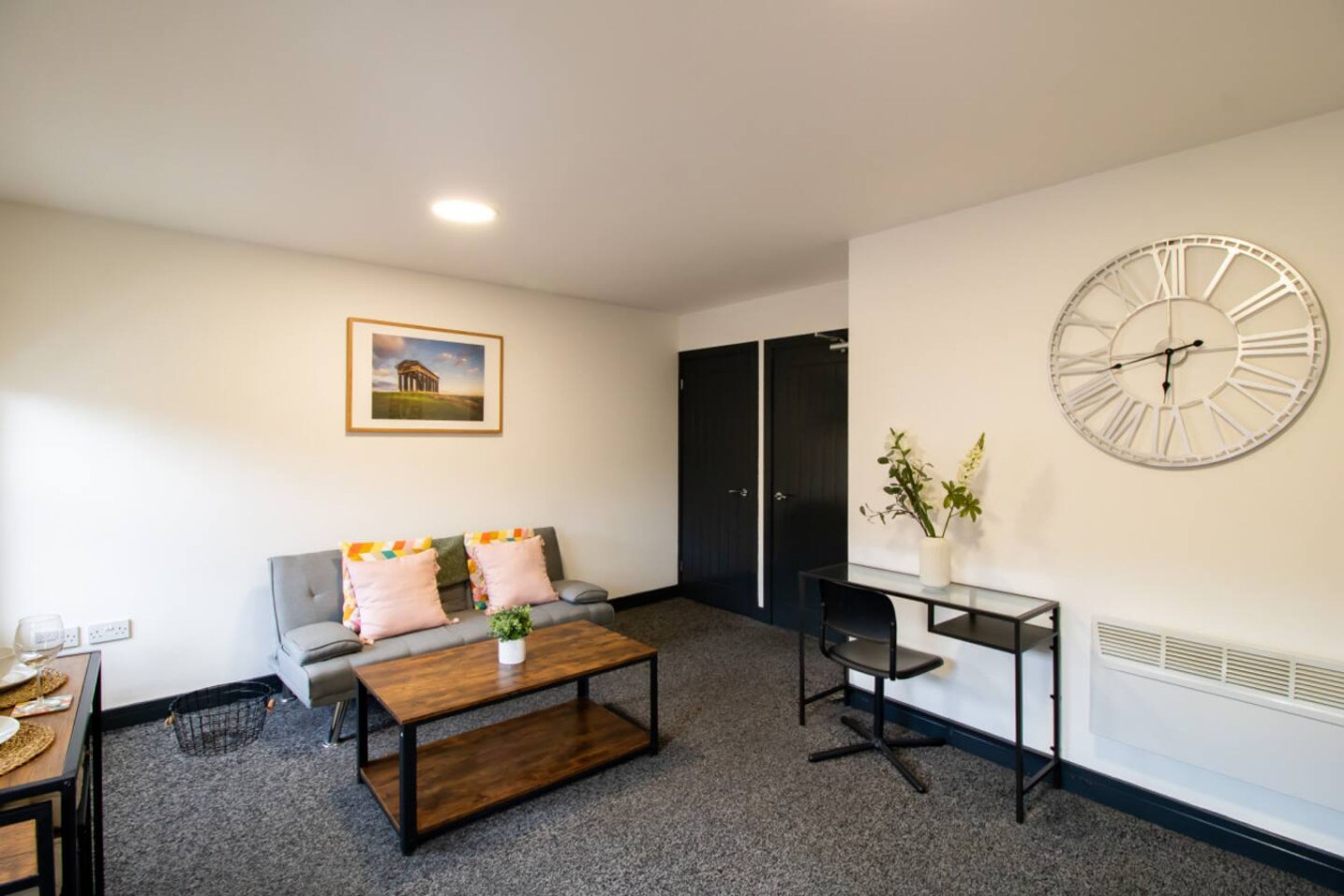 Ein Wohnzimmer mit Sofa, Couchtisch und einer Uhr an der Wand.