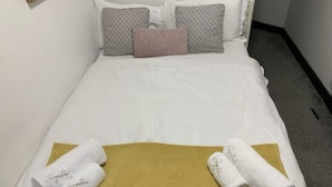 A neatly made bed with white linens, a mustard-colored blanket, and two towels with 'Signature' embroidered on them. - 1BR Urban Retreat in Central Sunderland (Sunderland)