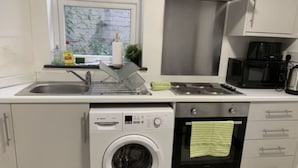 A compact kitchen with a washing machine, a microwave, and a sink. - 1BR Urban Retreat in Central Sunderland (Sunderland)