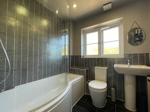A bathroom with a bathtub, toilet, and sink, featuring a window and a mirror. - 4BR 2bath Home in Colchester Perfect for Big Group (Colchester)