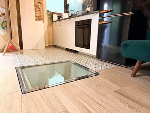 A kitchen with white cabinets, a black oven, a stainless steel refrigerator, and a glass table.