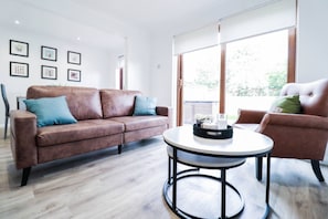 Ein modernes Wohnzimmer mit einem braunen Ledersofa, einem runden Couchtisch und einem braunen Ledersessel.