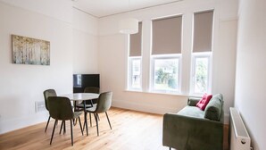 Ein Zimmer mit Esstisch, Stühlen, einer Couch und einem Fernseher.
