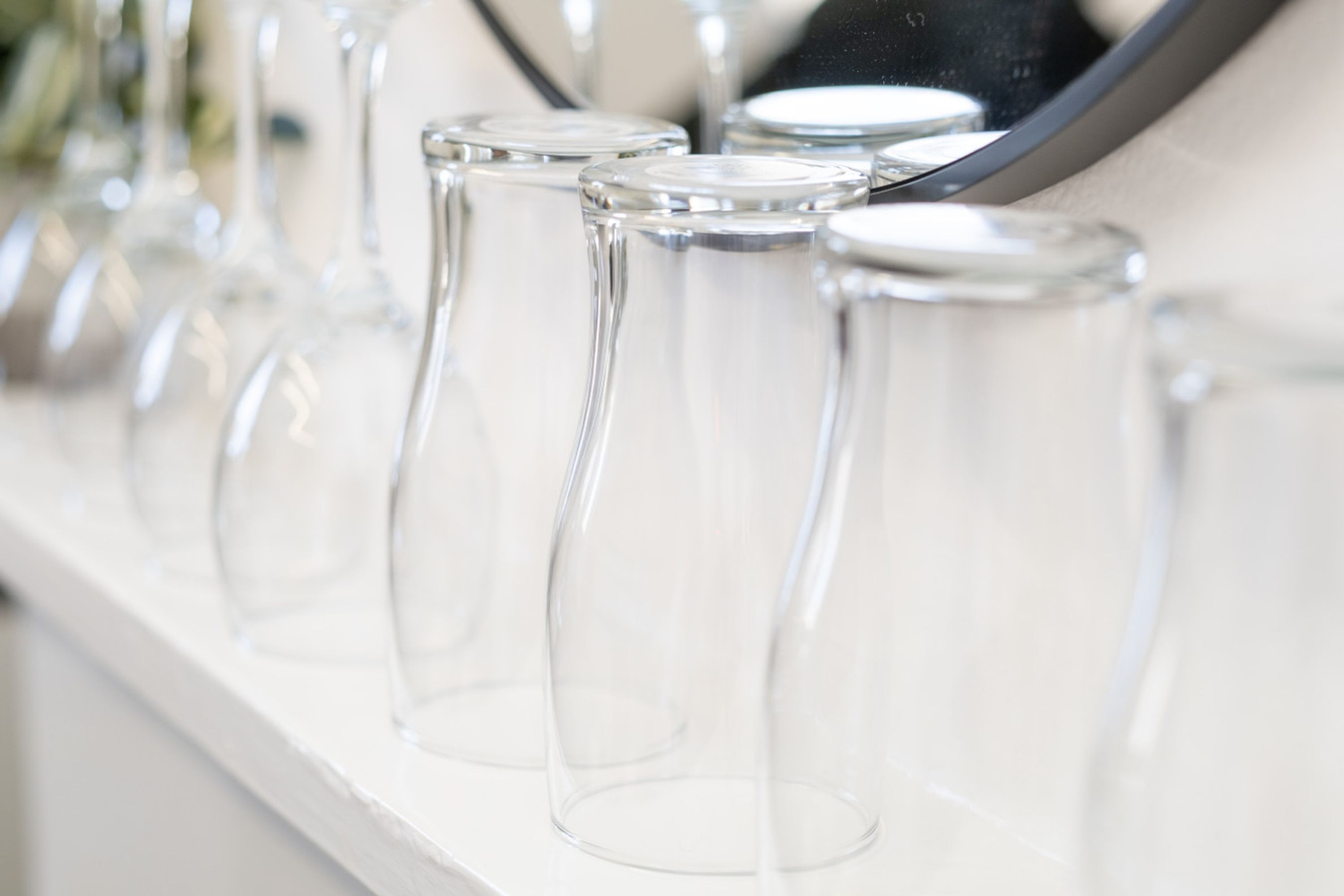 A row of clear glass wine glasses on a white surface.