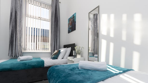 A hotel room with two beds, a large mirror, and a window with blinds. - Newly Renovated 3BR House Near Hospital uni (Sunderland)