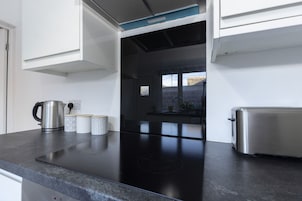 Una cocina moderna con encimera negra, electrodomésticos de acero inoxidable y ventana con vistas a la ciudad.