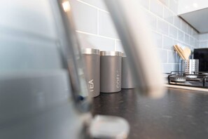 Stainless steel containers labeled 'TEA' and 'COFFEE' on a kitchen counter. - The Maple Haven Spacious 3BR w Free Parking (Jarrow)