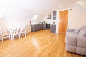 A modern kitchen with a dining area, a grey sofa, and a wooden floor. - Newly Renovated Sanctuary for 4 in Charlotte House (Ipswich)