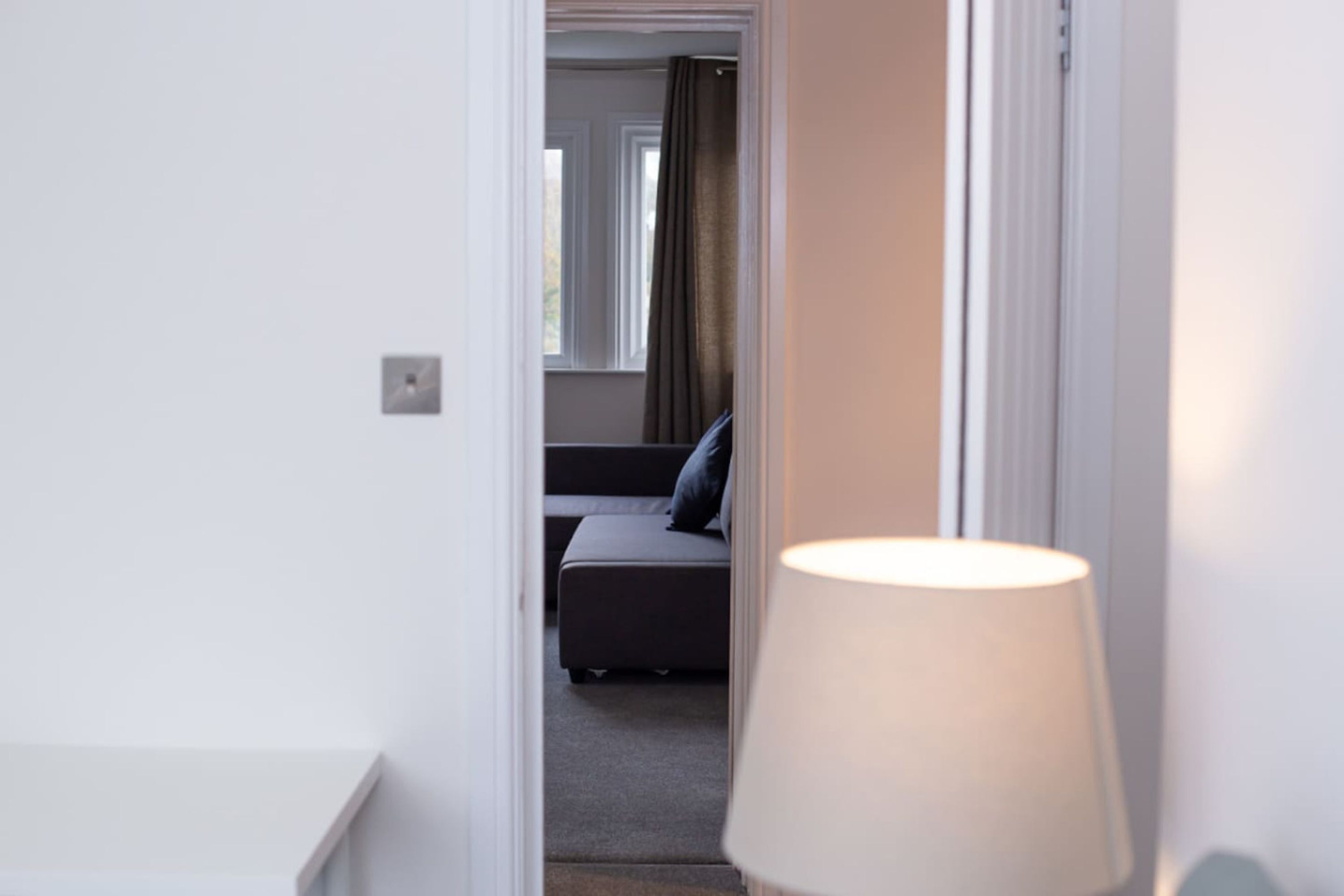 A doorway leading to a room with a sofa and a lamp.