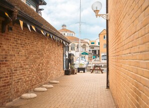 A narrow brick alleyway with a boat docked on the right, a lamp post, and a building with a dome in the background. - Cozy 1BR Seaside Apt in Brighton Marina Village (Brighton)