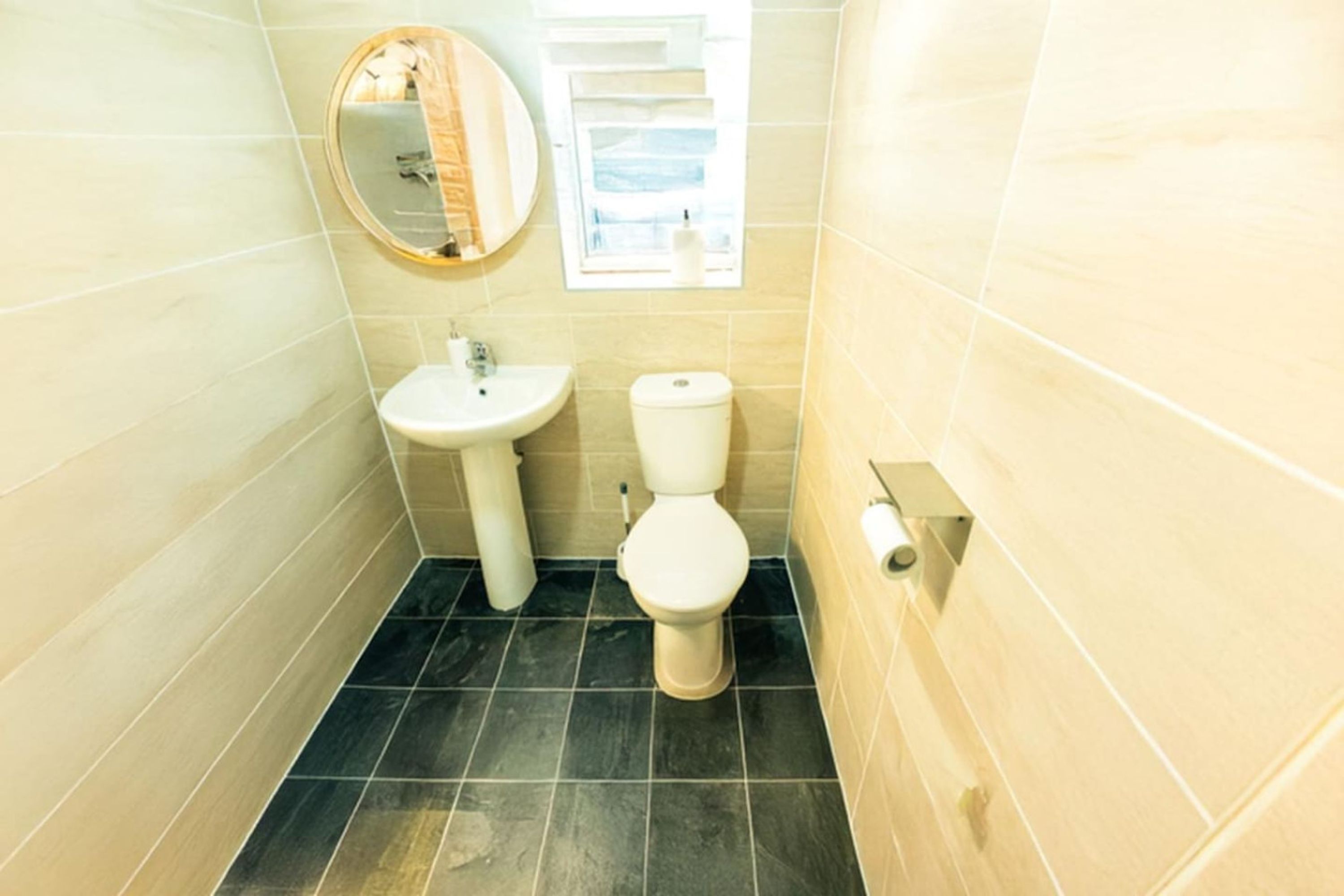 A bathroom with a sink, toilet, and a mirror.
