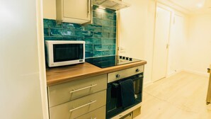 Eine kleine Küche mit Mikrowelle, Backofen und gefliestem Fliesenspiegel.