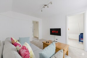 Un saló modern amb un sofà, una taula baixa i una televisió que mostra 'NETFLIX'.