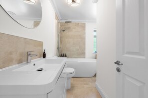 A modern bathroom with a bathtub, a toilet, and a sink. - Spacious 3BR Flat in Stroud Haven (Stroud)