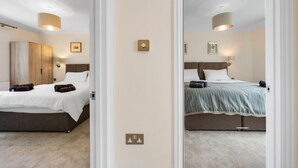 Ein Hotelzimmer mit zwei Betten, einem Kleiderschrank, einem Nachttisch und einer Lampe.