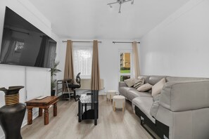 Een moderne woonkamer met een bank, een salontafel, een televisie en een eettafel.