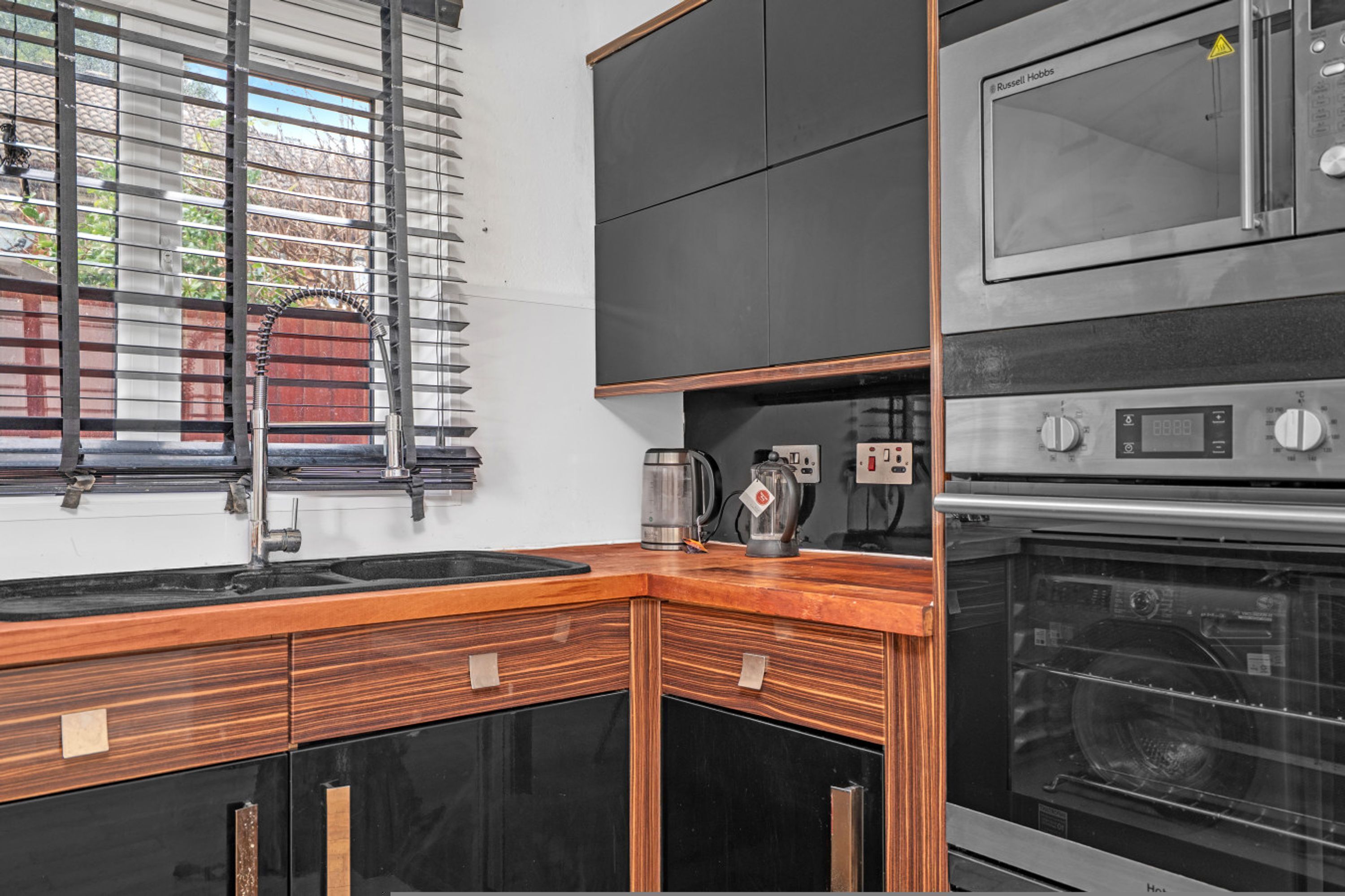A kitchen with a built-in oven, a microwave, and a coffee maker.