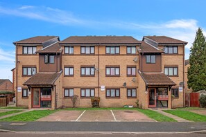 Un immeuble d’appartements à deux étages, doté d’une façade en briques, de nombreuses fenêtres et d’un espace de stationnement à l’avant.