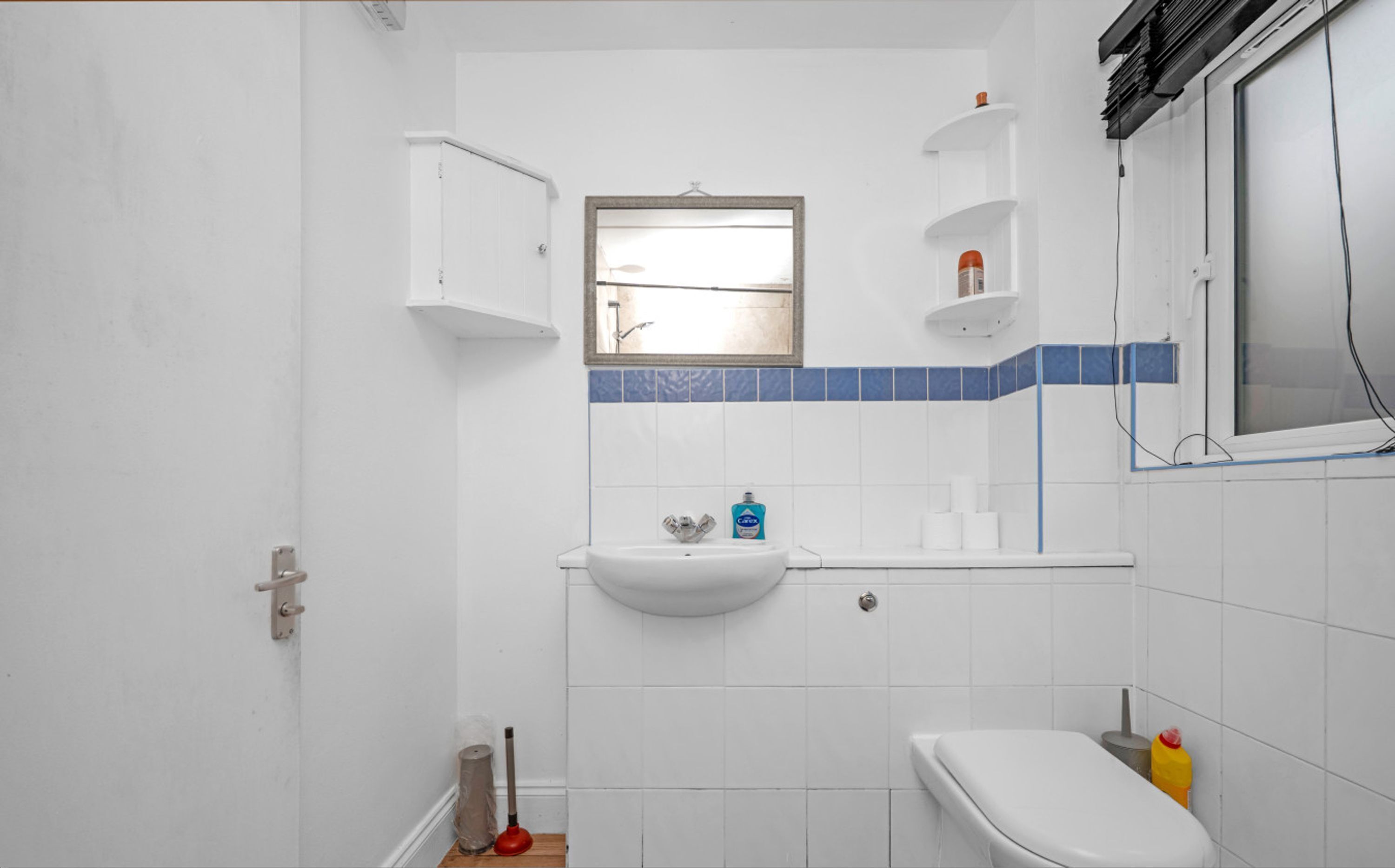 Een badkamer met een wastafel, toilet en raam.