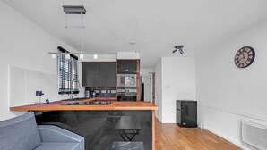 A modern kitchen with a wooden island, built-in appliances, and a grey sofa. - Cozy 1-bed Flat in Croydon Sleeps 4 - Free Parking (Croydon)