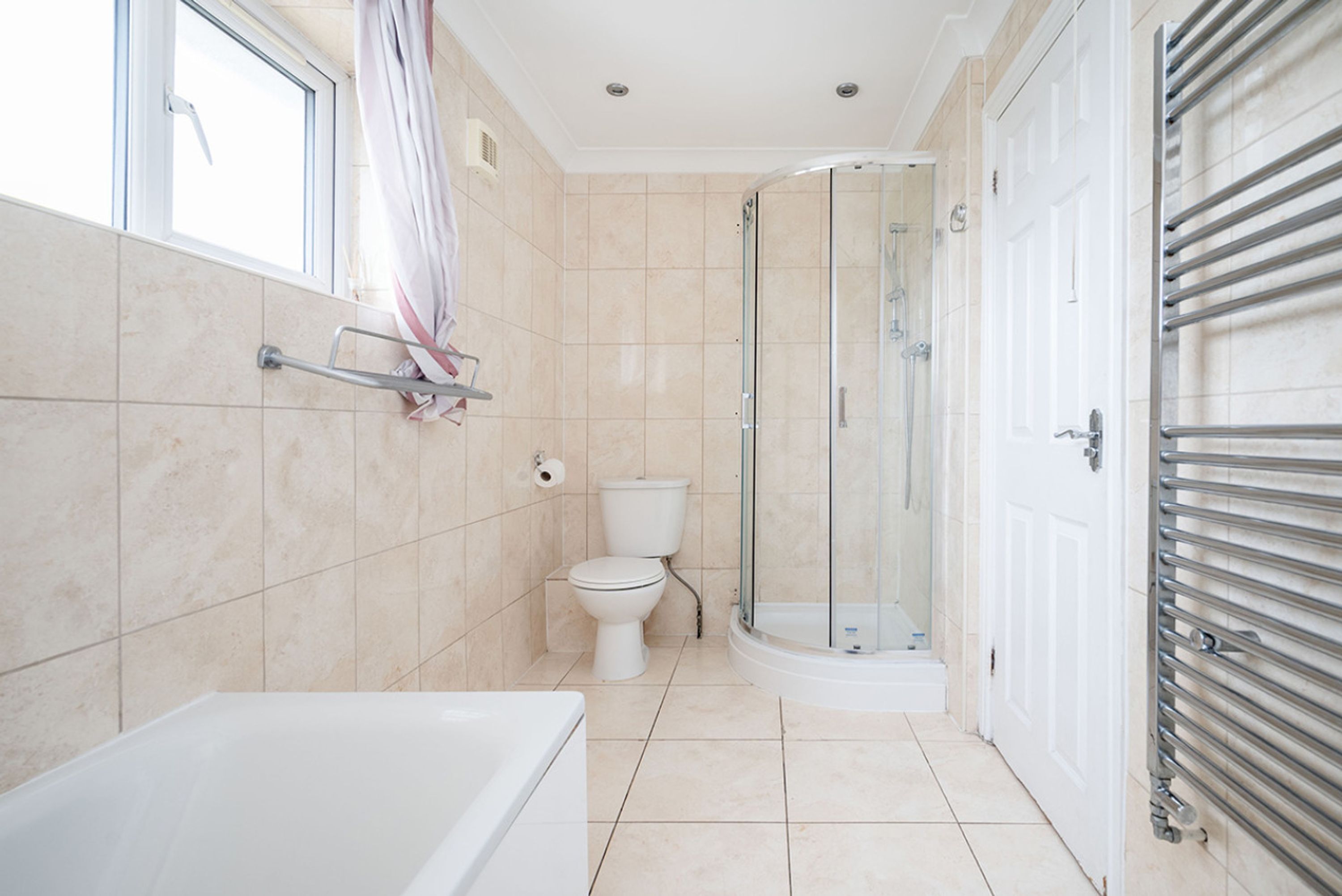 A bathroom with a bathtub, toilet, and glass-enclosed shower.