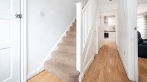 A staircase leading to a kitchen area with white walls and wooden flooring. - Family-friendly 3-bed Haven in Northolt w Parking (Northolt)