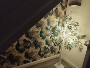 Ein Zimmer mit blumigem Wandpapier, einer weißen Stehlampe und einer Tür.