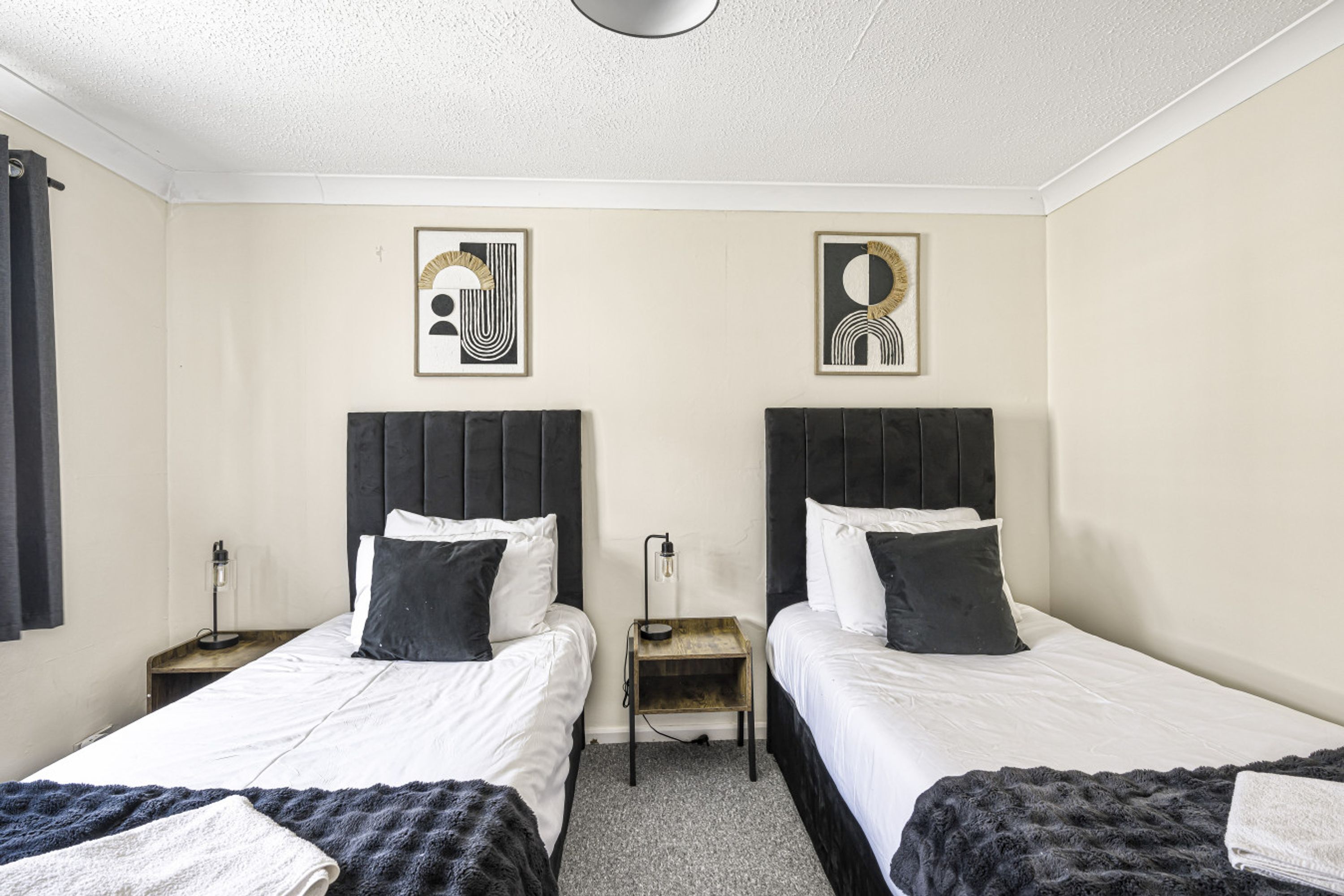 Ein Hotelzimmer mit zwei Betten, einem kleinen Nachttisch mit Lampe und einem Bild an der Wand.