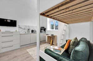 Eine moderne Küche mit weißen Schränken, einer Marmor-Spritzschutzwand und einer Holzbalkendecke.