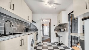 Una cucina moderna con pavimento a scacchi, mobili bianchi e lavatrice integrata.