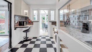 A modern kitchen with a checkered floor, white cabinets, and a black countertop. - Spacious 4-bedroom Haven in Orpington Retreat (Orpington)