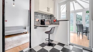 Una cucina compatta con forno a microonde, un piccolo sgabello da bar e un'area pranzo con tavolo e sedie.