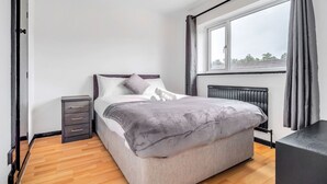 Una camera da letto con un letto, un comodino e una finestra con tende.