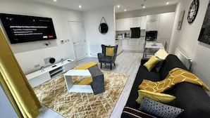 Ein modernes Wohnzimmer mit Fernseher, Sofa und Essbereich.