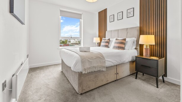 Ein modernes Schlafzimmer mit Bett, Nachttischen, einem Fenster und Blick.