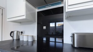 A modern kitchen with a black countertop, stainless steel appliances, and a window overlooking a cityscape. - Stylish 3BR Home With Parking by University (Sunderland)