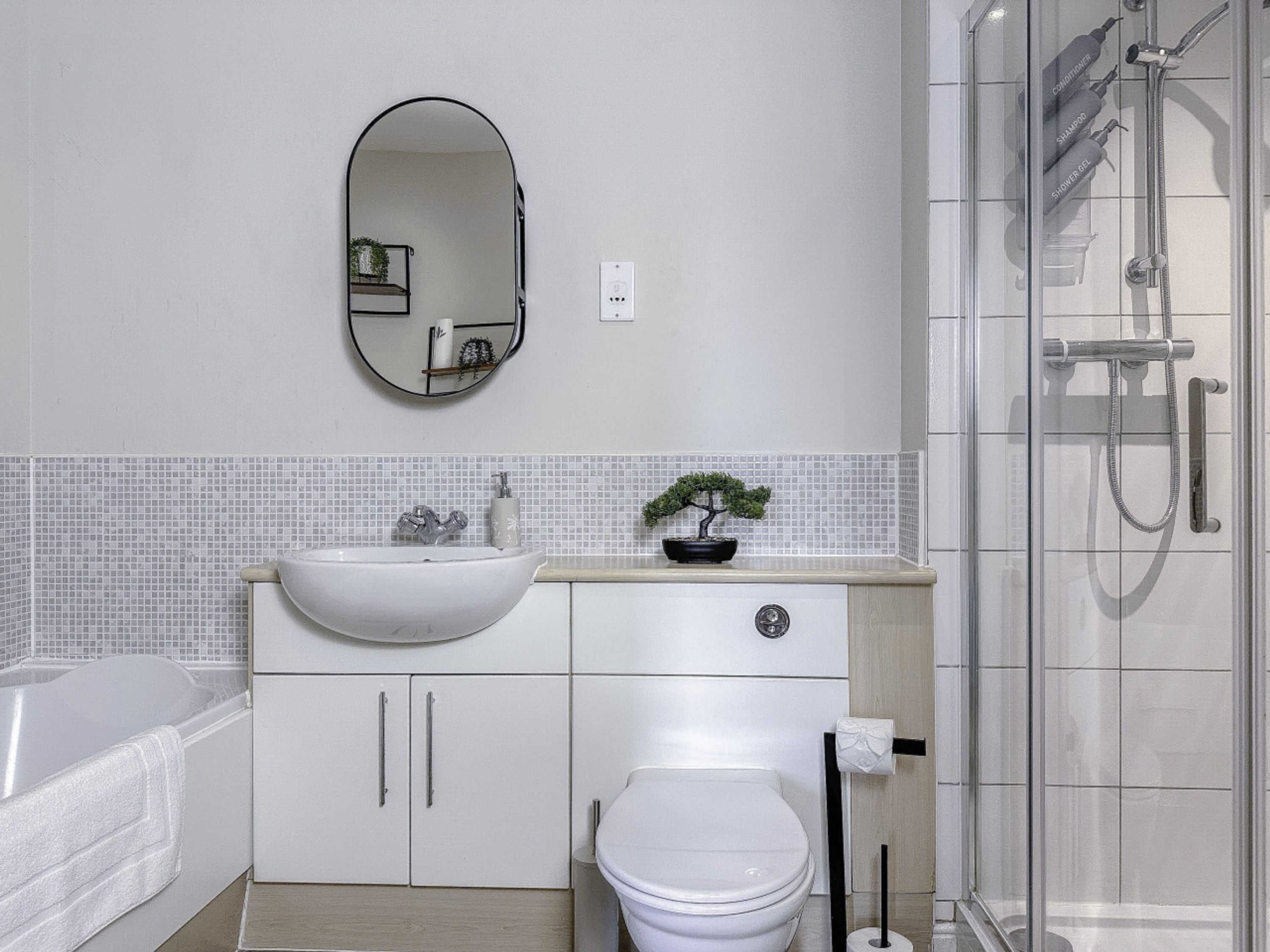 A bathroom with a white sink, a toilet, a mirror, and a shower.