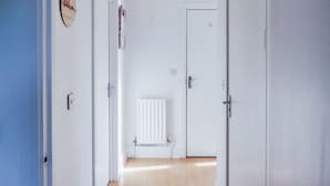 A hallway with a radiator, a door, and a hanging light fixture. - Elizabeth Line Retreat Modern 2BR Flat in Hayes (Hayes)